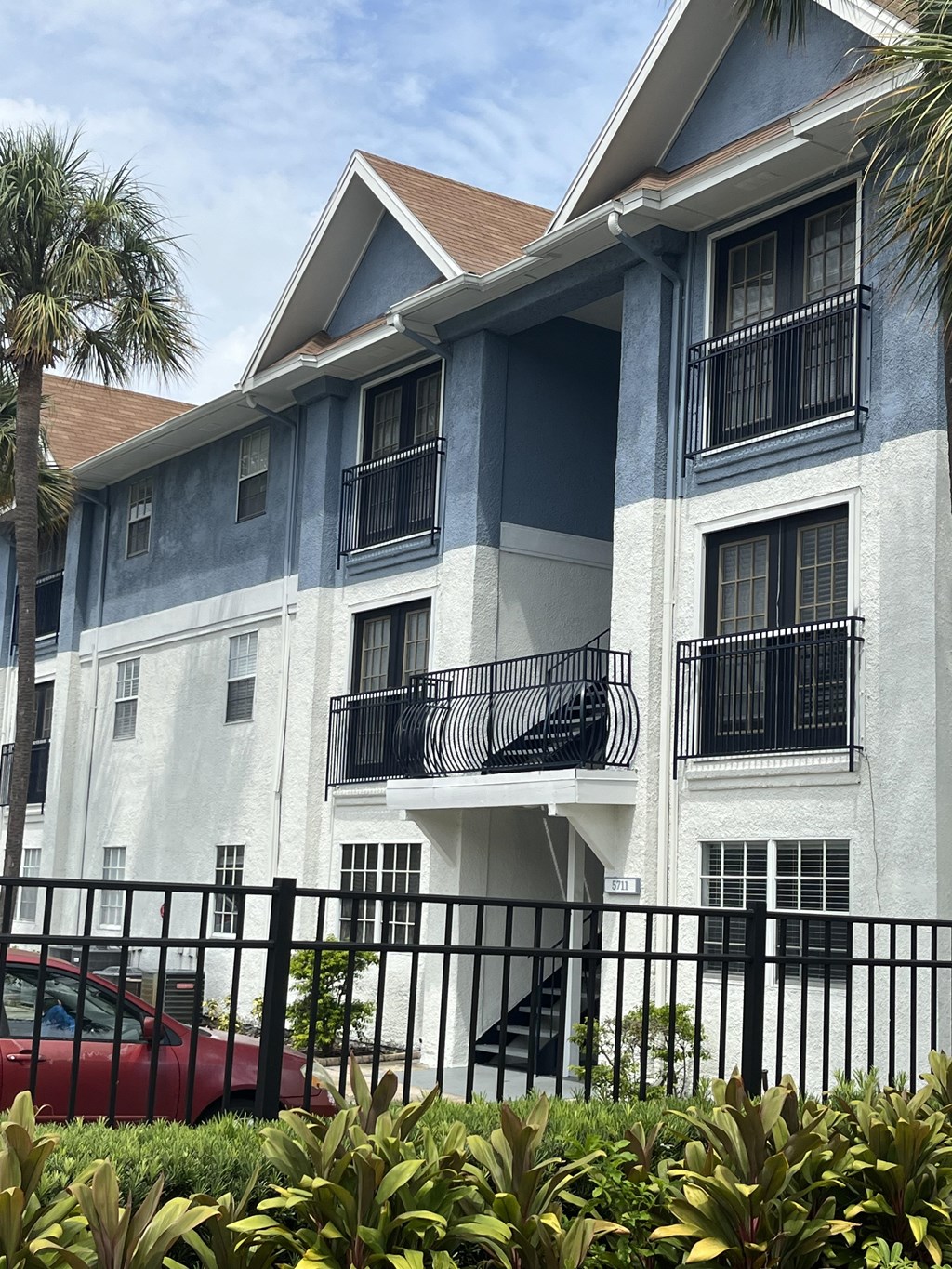 an apartment building with a red car parked in front of it